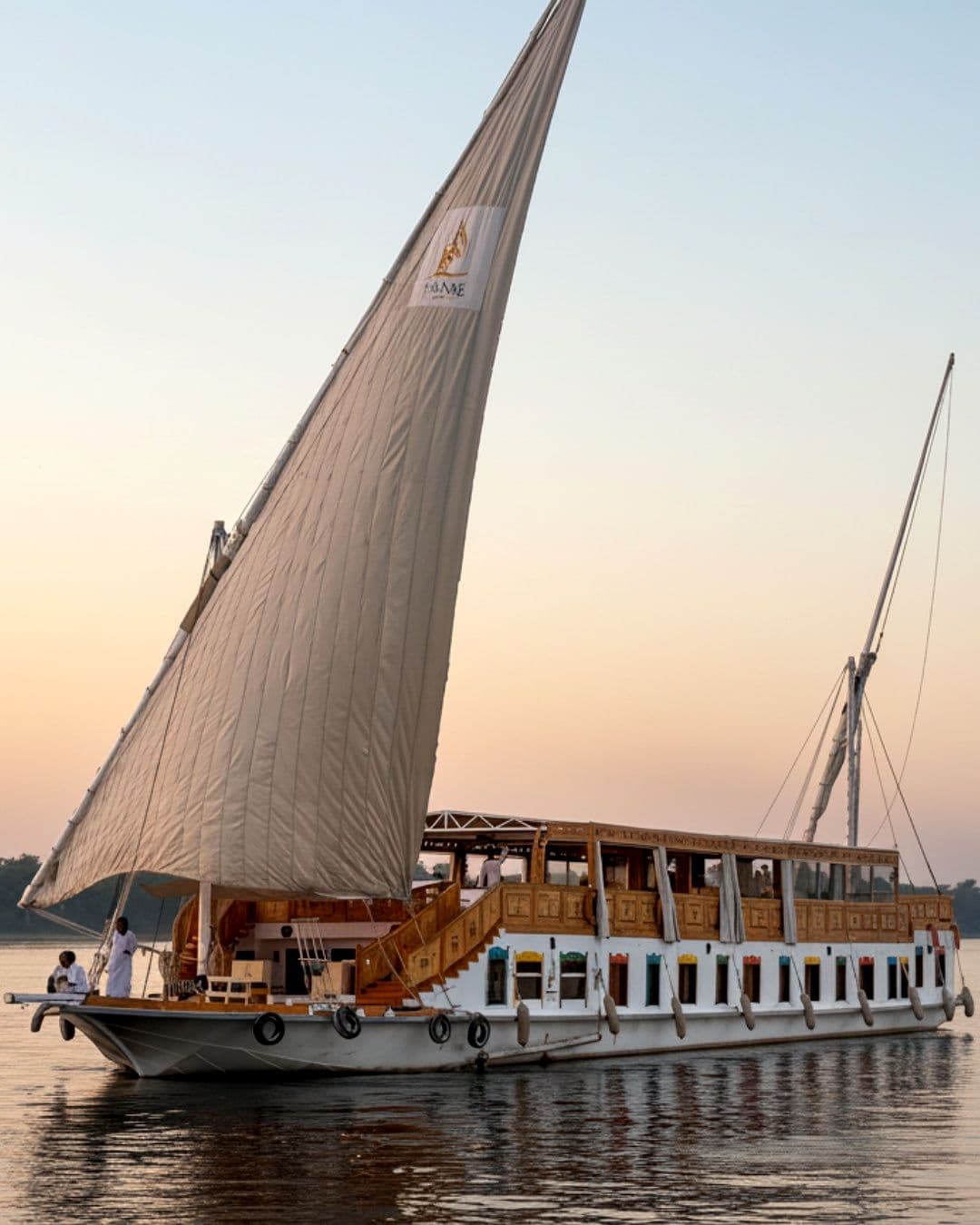 A traditional wooden dahabiya under sail on the Nile at sunset
